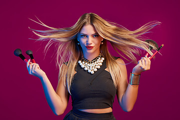 Image showing Female stylist with hair flying holding makeup brushes