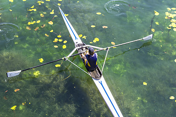 Image showing A Young single scull rowing competitor paddles on the tranquil l