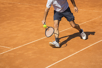 Image showing Male tennis player in action on the clay court on a sunny day