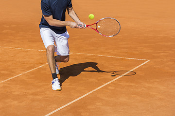 Image showing Male tennis player in action on the clay court on a sunny day