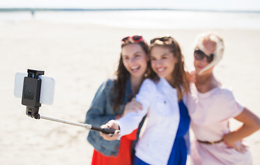 Image showing women with selfie stick and smartphone on beach