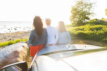 Image showing happy teenage girls or women near car at seaside