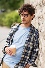 Image showing man in eyeglasses drinking coffee over street wall