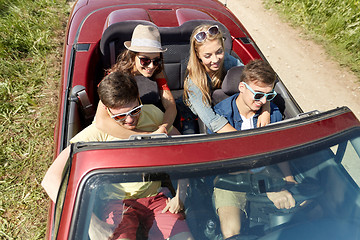 Image showing happy friends driving in cabriolet car at country