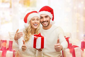 Image showing happy couple with christmas gifts and thumbs up