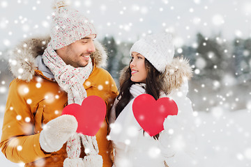 Image showing happy couple with red hearts over winter landscape