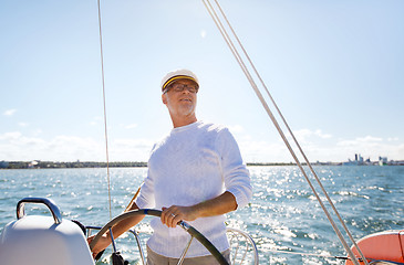 Image showing senior man at helm on boat or yacht sailing in sea