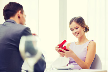 Image showing excited young woman looking at boyfriend with box