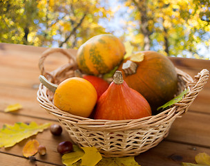 Image showing close up of pumpkins in basket on wooden table 