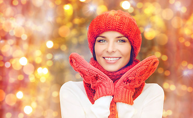 Image showing happy woman in hat, scarf and mittens over lights