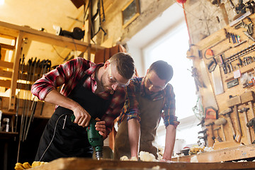 Image showing carpenters with drill drilling plank at workshop