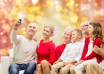 Image showing smiling family with camera over christmas lights