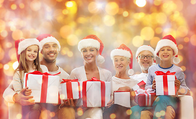 Image showing happy family in santa hats with gift boxes