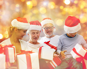 Image showing happy family in santa hats with gift boxes