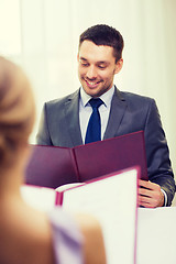 Image showing smiling young man looking at menu at restaurant