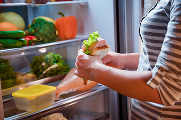 Image showing Hungry Woman holding a sandwich in his hands and standing next t