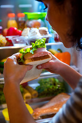 Image showing Hungry Woman holding a sandwich in his hands and standing next t