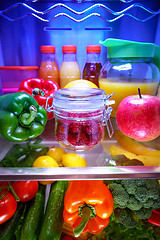 Image showing Fresh raspberries in a glass jar on a shelf open refrigerator