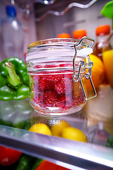 Image showing Fresh raspberries in a glass jar on a shelf open refrigerator