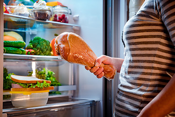 Image showing Hungry Woman holding a turkey leg in his hands and standing next