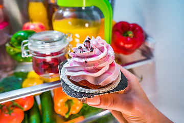 Image showing Woman takes the sweet cake from the open refrigerator