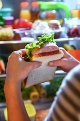 Image showing Hungry Woman holding a sandwich in his hands and standing next t