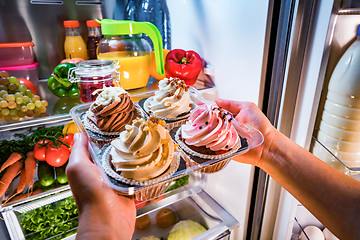 Image showing Woman takes the sweet cake from the open refrigerator