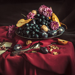 Image showing The fruit bowl with grapes and plums against a maroon tablecloth