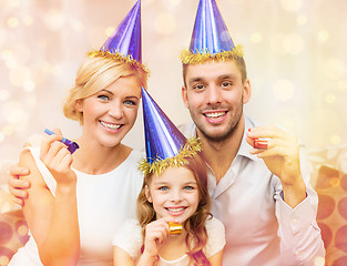 Image showing smiling family in blue hats blowing favor horns