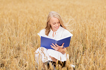 Image showing smiling young woman reading book on cereal field