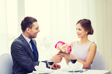 Image showing smiling man giving flower bouquet at restaurant