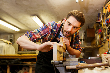 Image showing carpenter working with plane and wood at workshop