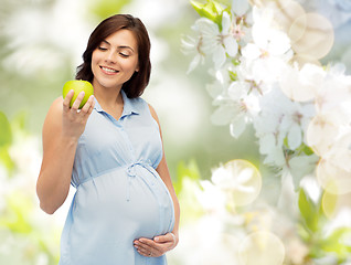 Image showing happy pregnant woman looking at green apple