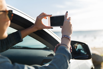 Image showing happy young woman in car with smartphone at sea