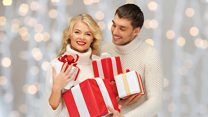 Image showing happy couple in sweaters holding christmas gifts