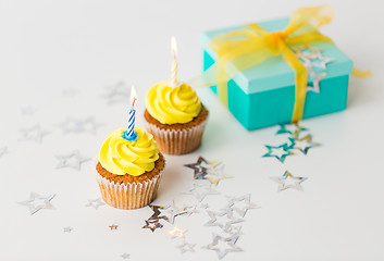 Image showing birthday cupcakes with burning candles and present