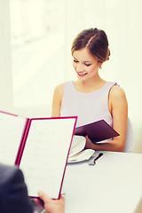 Image showing smiling young woman looking at menu at restaurant