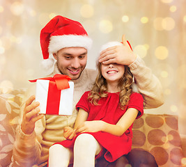 Image showing smiling father surprises daughter with gift box