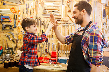 Image showing father and little son making high five at workshop