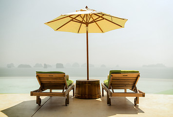 Image showing infinity pool with parasol and sun beds at seaside