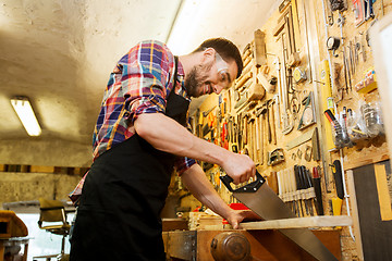 Image showing carpenter working with saw and wood at workshop