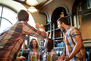 Image showing happy friends with beer celebrating at bar or pub