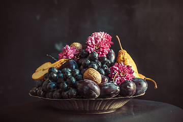 Image showing The fruit bowl with grapes and plums against a dark wall