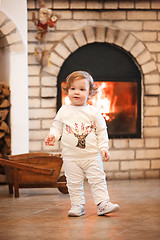 Image showing Happy child little girl standing at home against fireplace