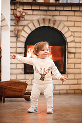 Image showing Happy child little girl standing at home against fireplace