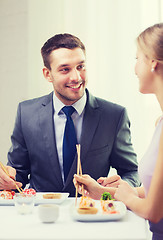 Image showing smiling couple eating sushi at restaurant