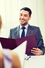 Image showing smiling young man with menu at restaurant