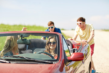 Image showing happy friends pushing broken cabriolet car