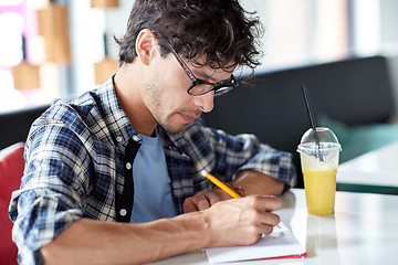 Image showing man with notebook and juice writing at cafe