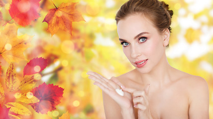 Image showing happy young woman with moisturizing cream on hand